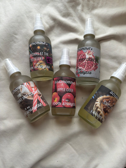 Five frosted glass spray bottles with different labels on a textured surface