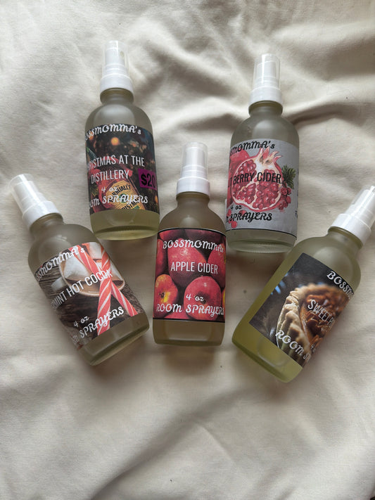 Five frosted glass spray bottles with different labels on a textured surface