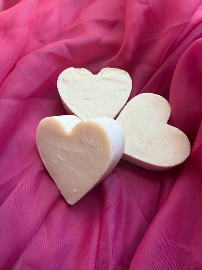 Three unfrosted heart-shaped soap bars on a pink fabric background