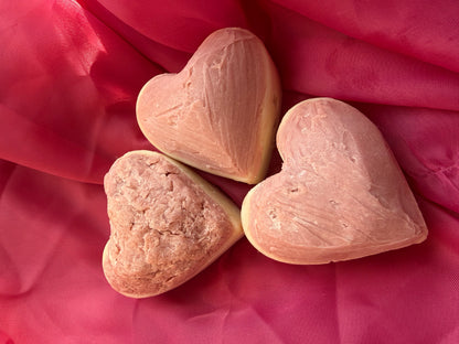 Three frosted heart-shaped soaps on a pink fabric background